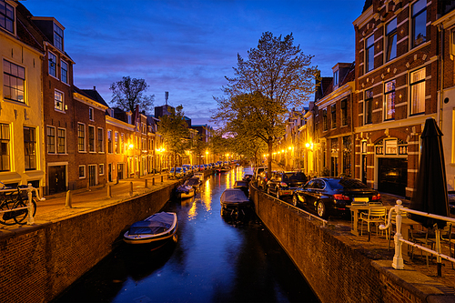 Typical Netherlands view - canal with boats and houses illuminated in the evening. Haarlem, Netherlands