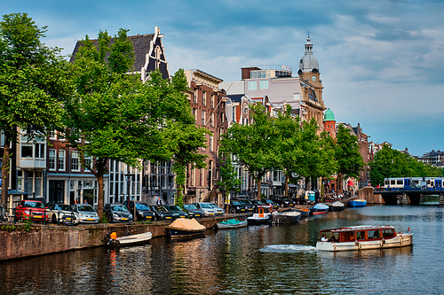 Amsterdam view - canal with tourist boat, bridge and old houses. Amsterdam, Netherlands