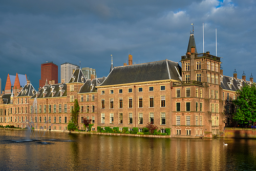 View of the Binnenhof House of Parliament and the Hofvijver lake with downtown skyscrapers in background. The Hague, Netherlands