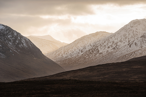 Stunning dramatic Winter sunset sunbeams over landscape of Lost Valley in Etive Mor in Scottish Highlands