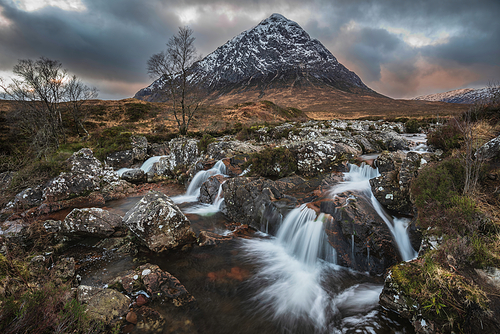 Stunning majestic Winter sunset landscape of Stob Dearg Buachaille Etive Mor iconic peak in Scottish Highlands with famous River Etive waterfalls in foreground