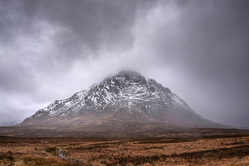 Winter landscape image of Stob Dearg Buachaille Etive Mor viewed from Rannoch Moor with snowcapped peak and beautiful dramatic cloud formations