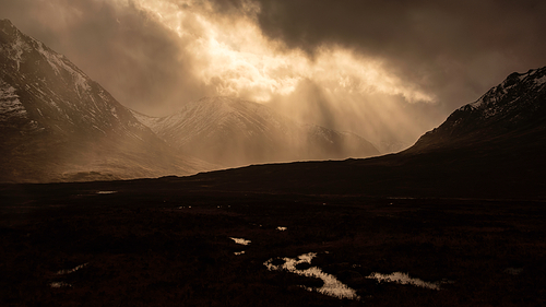 Stunning dramatic Winter sunset sunbeams over landscape of Lost Valley in Etive Mor in Scottish Highlands