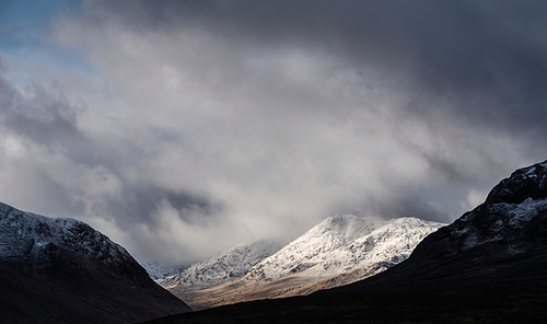 Stunning beautiful Winter landscape image of Lost Valley in Scotland with snowcapped Buachaile Etive Baeg sand distant mountain range with dramatic sky