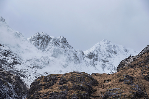 Epic Winter landscape image of snowcapped Three Sisters mountain range in Glencoe Scottish Highands with dramatic sky