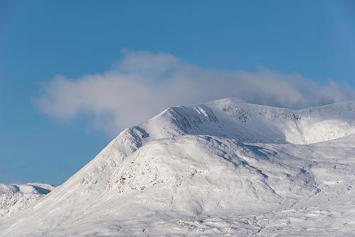 Majestic Winter landscape image looking towards Scottish Highlands mountain range across Loch Ba on Rannoch Moor