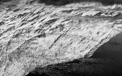 Black and white Beautiful Winter landscape image of Loch Achtriochan in Scottish Highlands with stunning reflections in still water with crytal clear blue sky