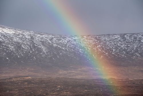 Stunning landscape image of vibrant rainbow in front of mountains in Scottish Highlands Rannoch Moor Stob Dearg