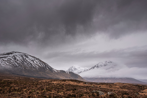 Winter landscape of Buachaille Etive Mor Stob Dearg in Scottish Highlands engulfed in low cloud with snowcapped peaks