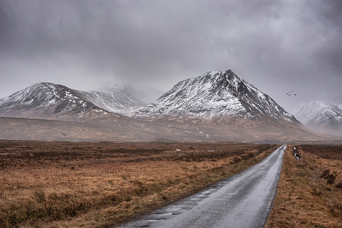 Beautiful moody Winter landscape image of Lost Valley Etive Mor in Scottish Highlands wirth dramatic clouds overhead