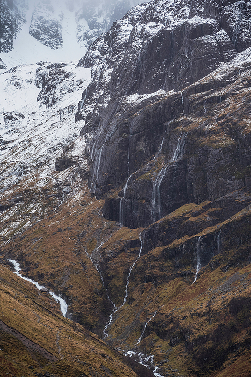 Epic Winter landscape image of snowcapped Three Sisters mountain range in Glencoe Scottish Highands with dramatic sky