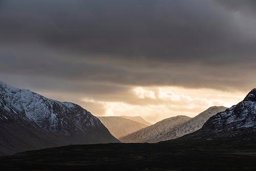 Stunning dramatic Winter sunset sunbeams over landscape of Lost Valley in Etive Mor in Scottish Highlands