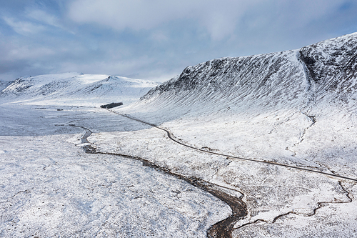 Stunning aerial drone landscape image of Stob Dearg and Glencoe in Scottish Highlands during deep snowfall and beautiful blue skies