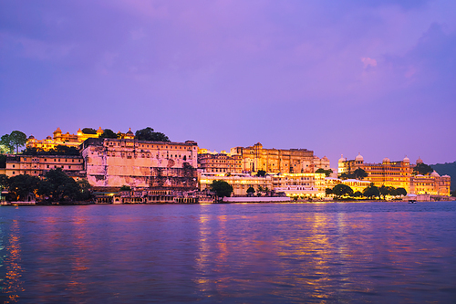 View of famous romantic luxury Rajasthan indian tourist landmark - Udaipur City Palace in the evening twilight with dramatic sky - panoramic view. Udaipur, India