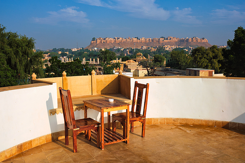 Rooftop Table with chairs with view of tourist landmark of Rajasthan - Jaisalmer Fort known as the Golden Fort Sonar quila, Jaisalmer, Rajasthan, India