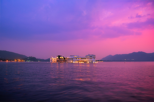 Romantic luxury India travel tourism - Lake Palace (Jag Niwas) complex on Lake Pichola on sunset in twilight with dramatic sky, Udaipur, Rajasthan, India