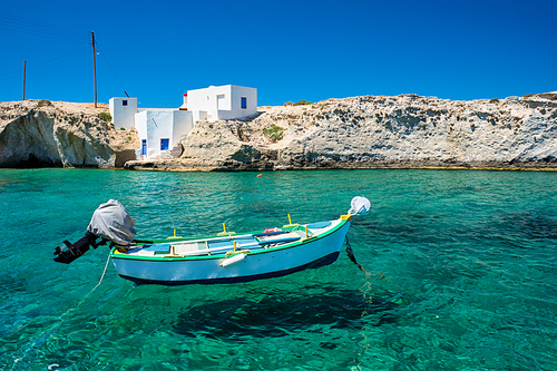 Greece scenic island view - small harbor with fishing boats in crystal clear turquoise water, traditishional whitewashed house. Mitakas village, Milos island, Greece.