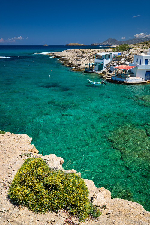 Greece scenic island view - small harbor with fishing boats in crystal clear turquoise water, traditishional whitewashed house. MItakas village, Milos island, Greece.