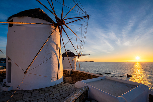 Scenic view of famous Mykonos town windmills. Traditional greek windmills on Mykonos island on sunset with dramatic sky, Cyclades, Greece. Walking with steadycam.