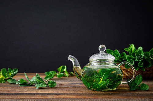 Mint tea, fresh herbal drink in a glass teapot with fresh leaves