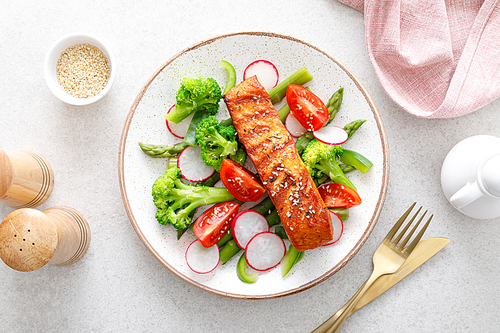 Salmon fish fillet grilled and vegetable salad with radish, tomato, green pepper, broccoli and asparagus.