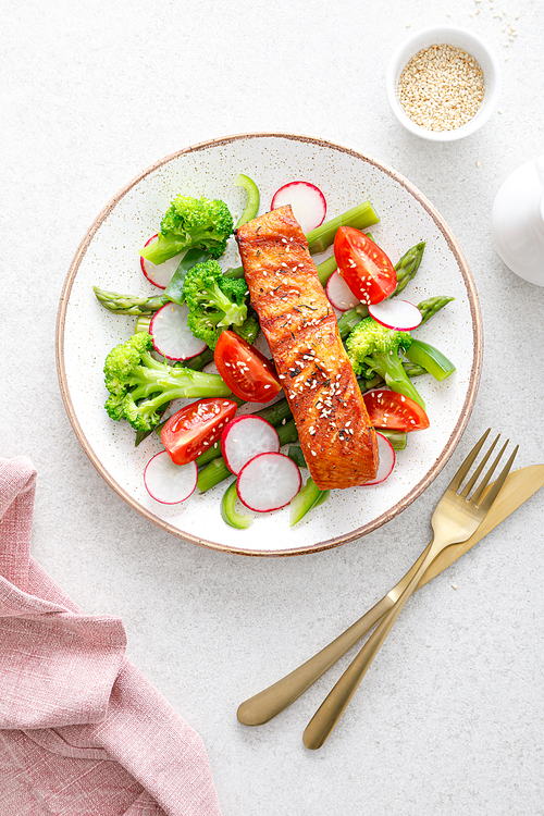 Salmon fish fillet grilled and vegetable salad with radish, tomato, green pepper, broccoli and asparagus.