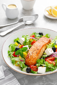 Salmon fish salad. Fresh vegetable greek salad with tomato, pepper, lettuce, olives, cucumbers, feta cheese and grilled salmon fish fillet in bowl, healthy food, omega 3, keto diet, mediterranean cusine.