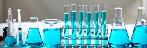 Chemistry laboratory glassware, science laboratory research and development concept, flask, beaker, and test tubes with blue liquid water sample test, scientific test tubes equipment