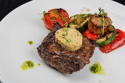 Grilled black angus strip loin steak with vegetables on white plate on black wooden background