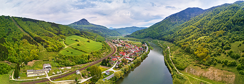 Village, river and road in mountain valley. Green mountain meadows and hills. Kra?oviansky meander on river Bar. Spring panorama. Overcast dramatic sky. Slovakia Tatras range.