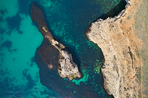 Aerial shot of beautiful rock beach with clear turquoise sea water. Nature composition.