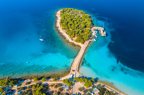 Aerial view of beutiful small island in sea bay at sunrise in summer in Murter, Croatia. Top view of transparent blue water, green trees, mountain, sandy beach, boats and yachts. Tropical landscape