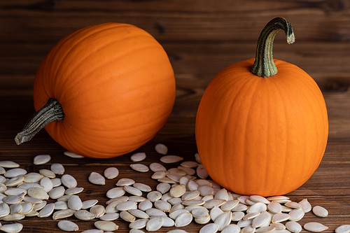 Small ripe pumpkins and seeds on wooden backdrop