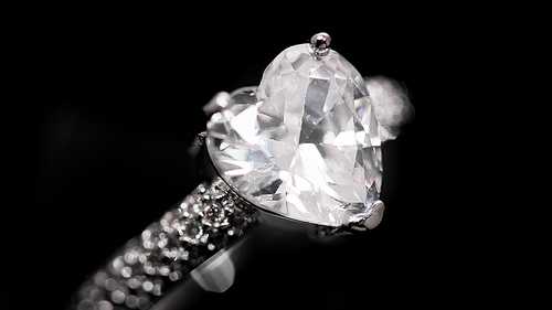 Engagement diamond ring rotating on black background. Heart cut diamond. Traditional piece of jewelry, macro shot.