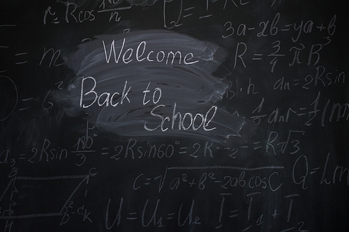 welocome back to school written with chalk words on blackboard with math formulas in background