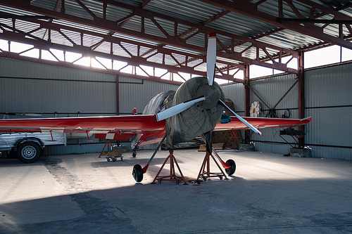 Small private lightweight propeller airplanes in hangar.