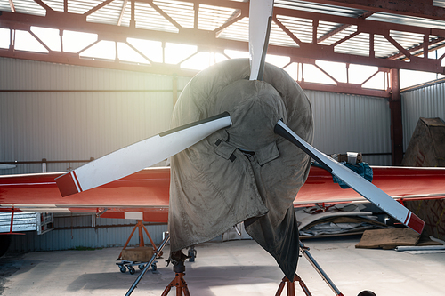 Small private lightweight propeller airplanes in hangar.