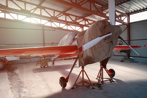 Small private lightweight propeller airplanes in hangar.