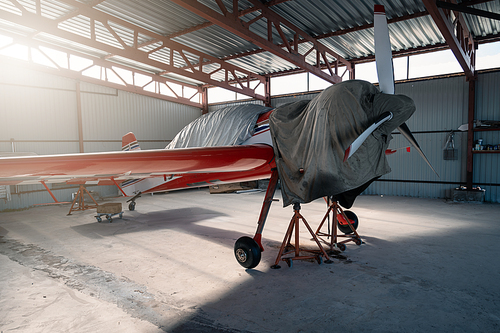 Small private lightweight propeller airplanes in hangar.