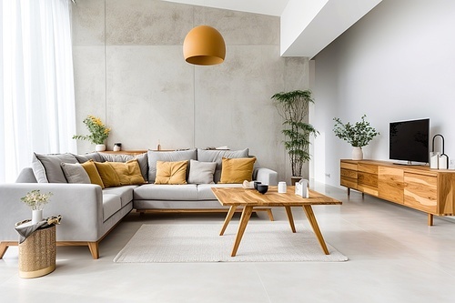 Grey sofa with yellow pillows in room with tv unit. Minimalist loft home interior design of modern living room with concrete wall.