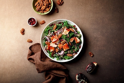 Salmon superfood salad with grilled fish, kale, quinoa, pecan nuts, red onion and pomegranate. Top view