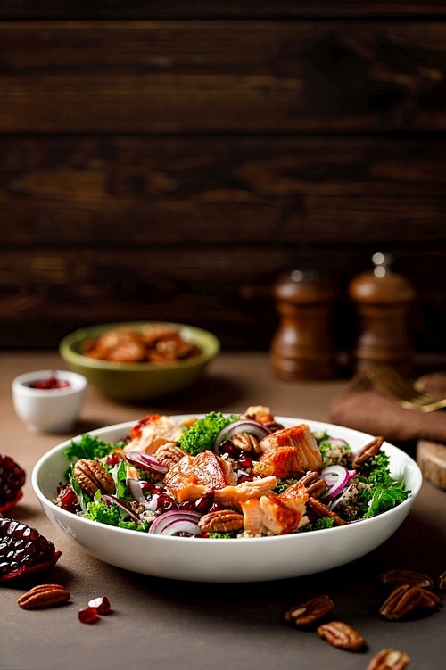 Salmon superfood salad with grilled fish, kale, quinoa, pecan nuts, red onion and pomegranate