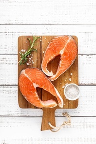 Fresh raw salmon steaks on a board with ingredients for cooking, top view