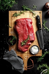 Beef meat entrecote on a cutting board, raw beef meat fillet on black background, top view