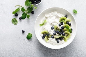 White plain greek yogurt with fresh blueberries and kiwi fruit, top view