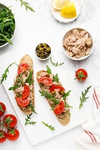 Tuna caper toasts with arugula, tomatoes and whole rye bread, top view