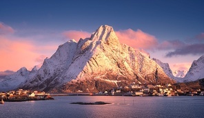 Snowy mountain, sea, islands with houses and rorbu, purple sky with pink clouds at sunrise in winter. Reine, Lofoten islands, Norway. Colorful landscape with rocks in snow, rorbuer in fishing village