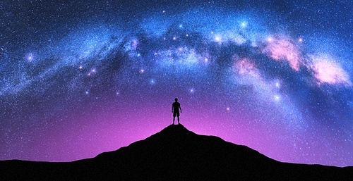 Milky Way arch and man on the mountain peak at starry night. Silhouette of alone guy, pink sky with bright stars in summer. Galaxy. Space background. Landscape with arched milky way. Travel and nature