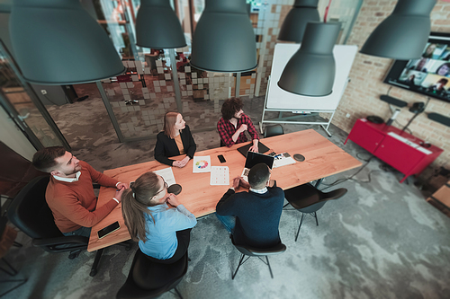 Top view of young multi-ethnic business people working and communicating together in creative office. Selective focus. High-quality photo