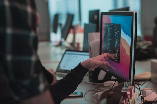 A photo of three men staring intently at a computer while sitting in a modern office. Selective focus. High-quality photo